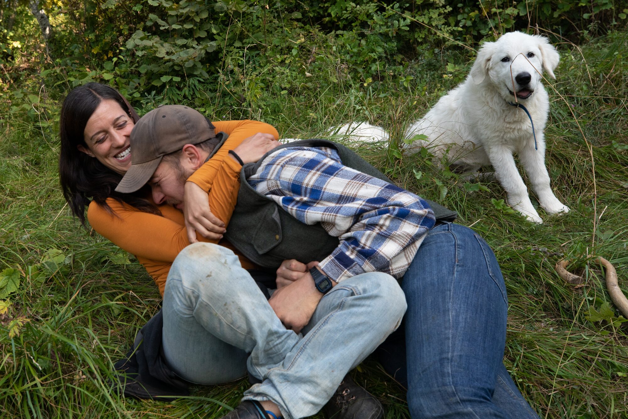 Sofia e Mattia sorridono insieme sull’erba accanto al loro cane da guardiania